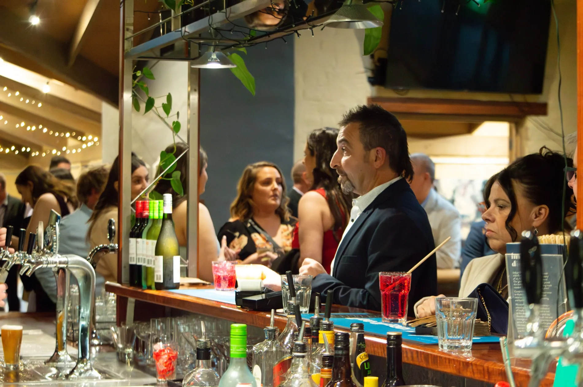 The Bridges bar on a busy night, strung with warm lights, guests talking along the counter.