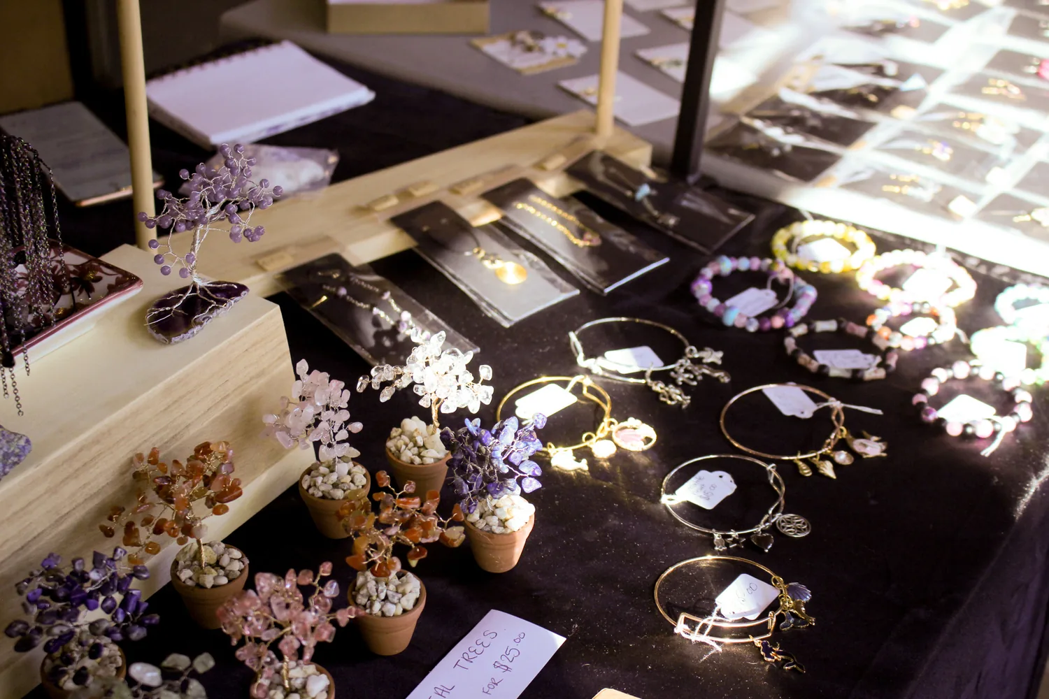 A market stall of handmade jewellery and dried flowers laid out on dark cloth.